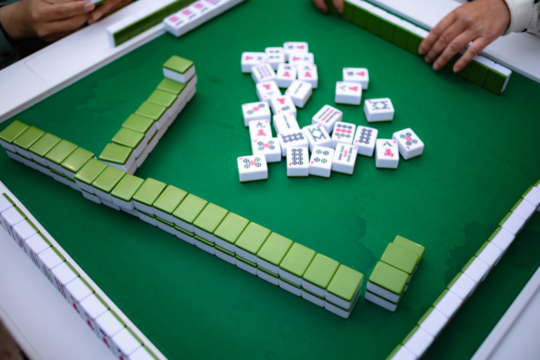 Players gathering tiles around a mahjong table